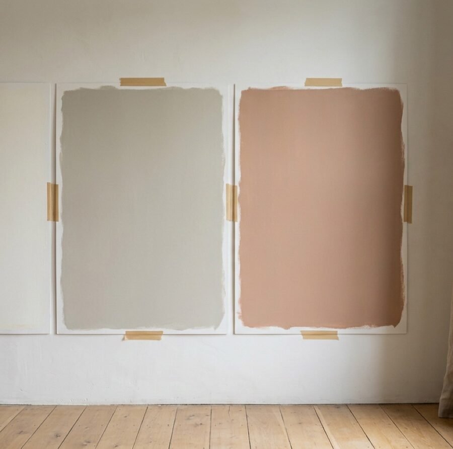 Paint sample boards taped to a wall beside a window in soft daylight